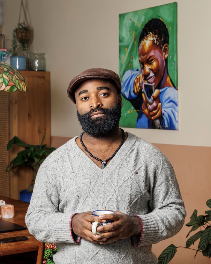 Kiza Magendane thuis, met een mok in zijn handen.